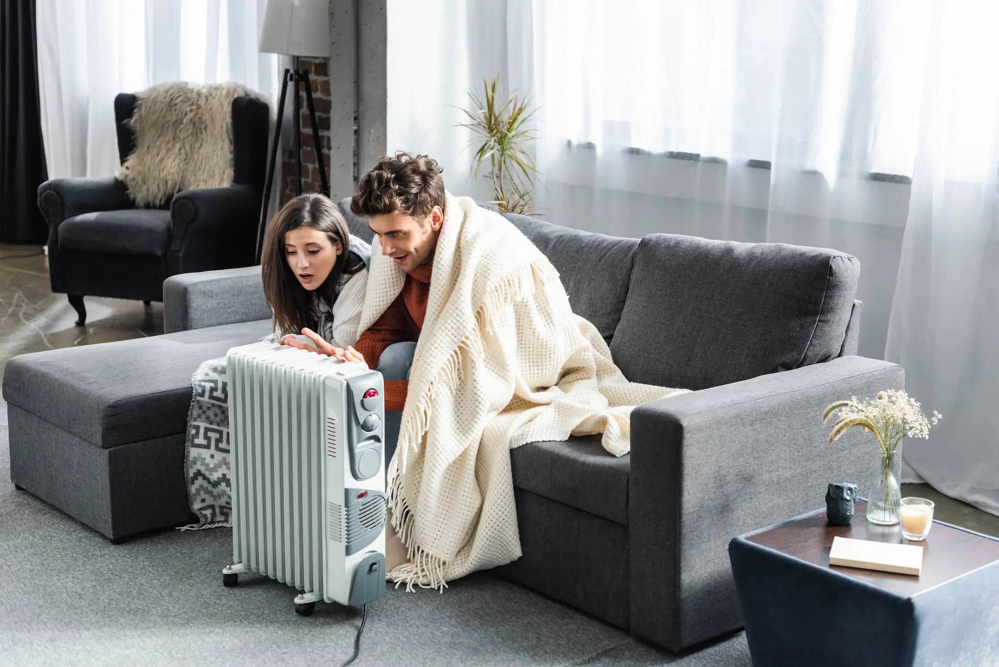 attractive girlfriend and boyfriend covered with blankest warming up near heater